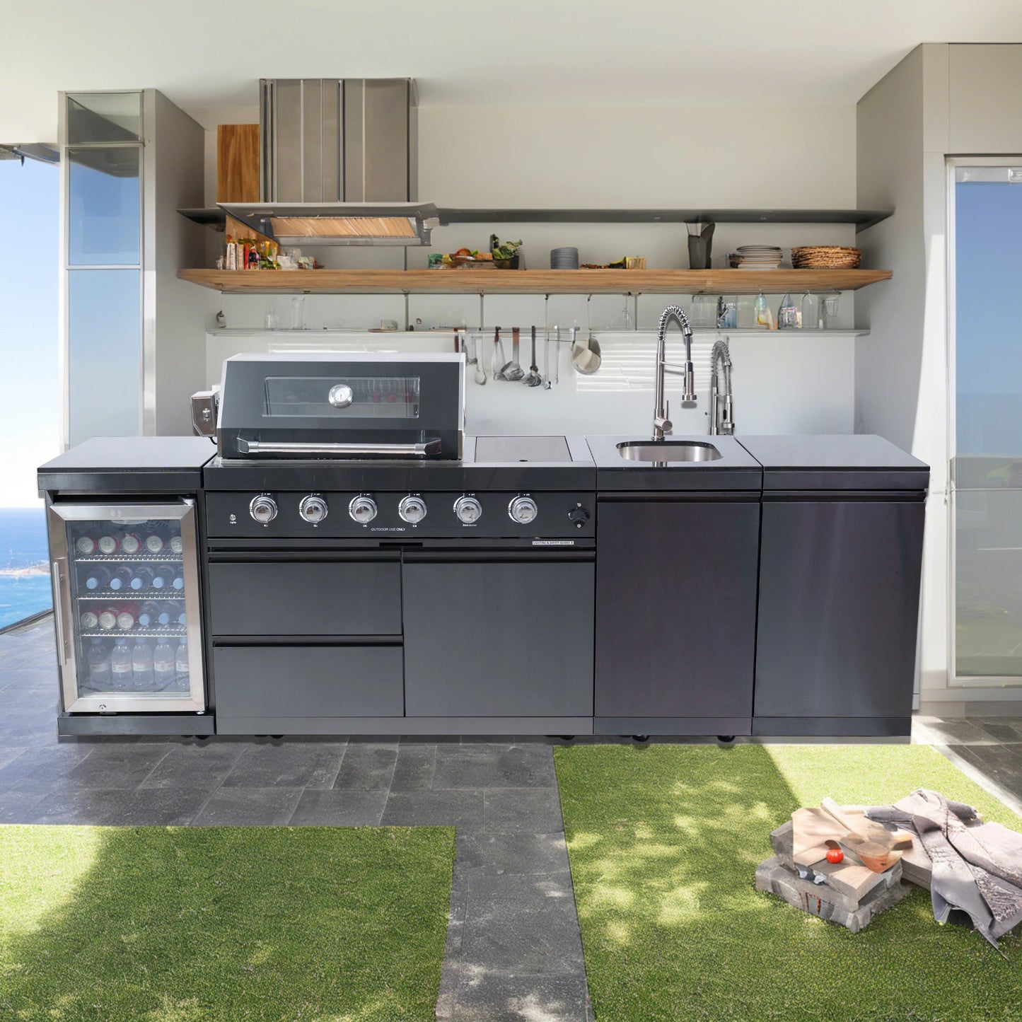 Modern outdoor kitchen with grill, sink, and refrigerator in a backyard setting.